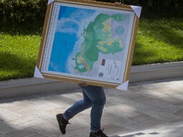 Un hombre carga un cuadro del mapa de Venezuela con la adhesión del Esequibo.