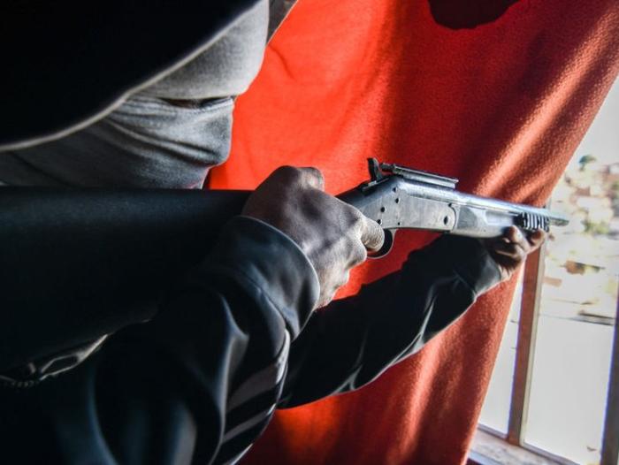 BBC Mundo: Un hombre sostiene una escopeta frente a una ventana en un barrio de Caracas.